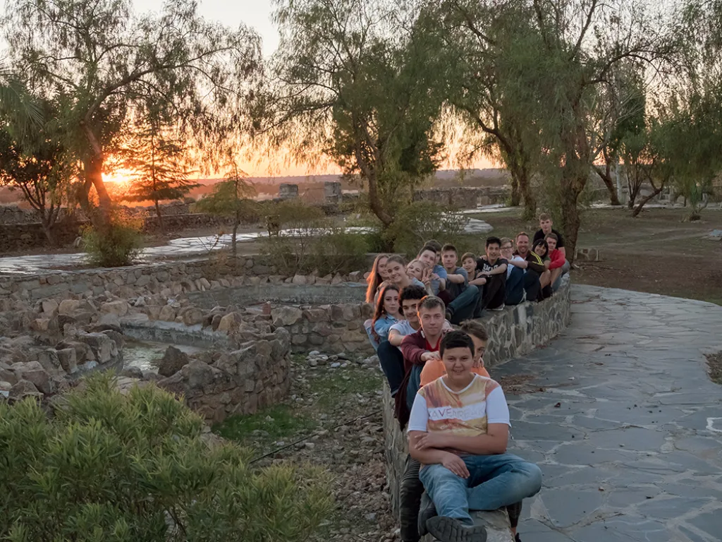 Die Gruppe sitzt bei Sonnenuntergang auf einer Mauer im Park.